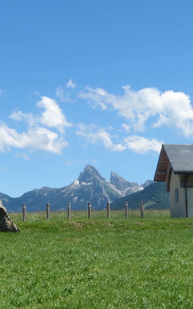 Chapelle de Champeillant against a blue sky and green grass. The Dent d'Oche peak stands out in the background.