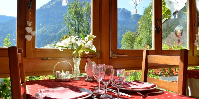 Tafel klaar om een maaltijd te serveren, rood tafelkleed, bloemen in een vaas en uitzicht op de berg