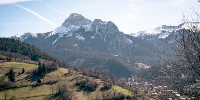 Dent d'oche enneigée et village en dessous sans neige avec une belle herbe verte de printemps