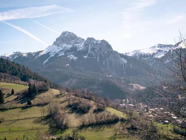 Dent d'oche enneigée et village en dessous sans neige avec une belle herbe verte de printemps