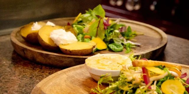 Un plat fromager avec une salade sur un plateau en bois