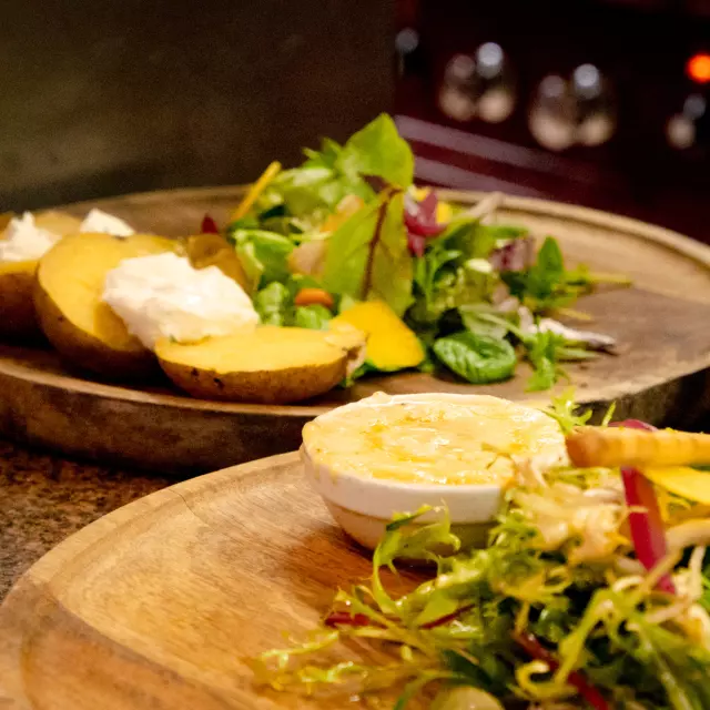 Un plat fromager avec une salade sur un plateau en bois