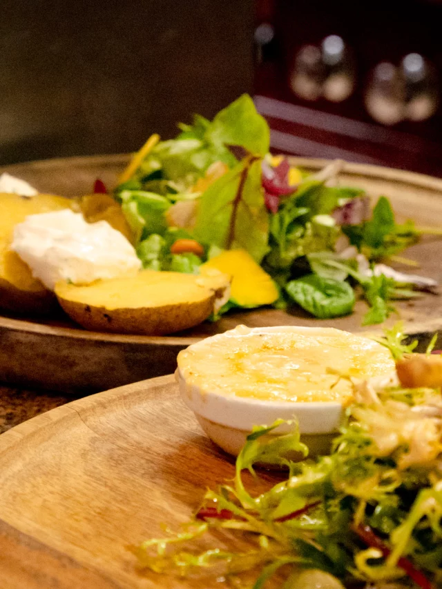 Un plat fromager avec une salade sur un plateau en bois