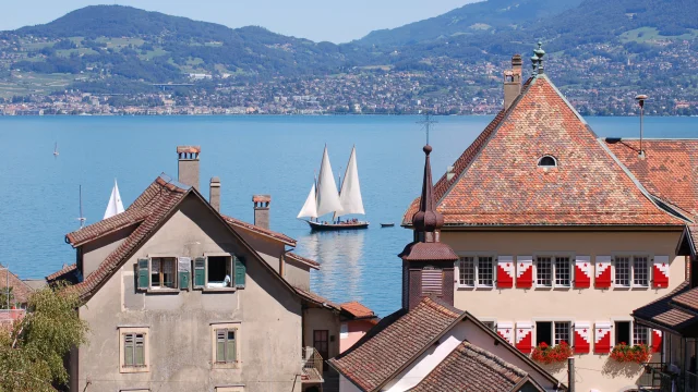 Vue sur le lac, on voit un voilier sur l'eau et les bâtiments de St Gingolph en premier plan