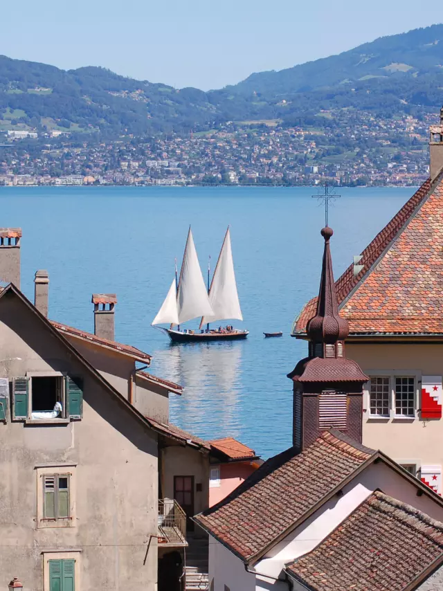 Vue sur le lac, on voit un voilier sur l'eau et les bâtiments de St Gingolph en premier plan