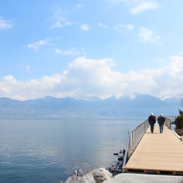 Two people walking on a pontoon by the lake